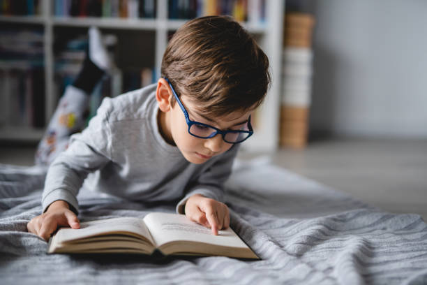 하루에 집에 누워 있는 백인 소년 한 명이 책 앞면 복사 공간 실제 사람 교육 개념을 읽습니다. - 읽기 뉴스 사진 이미지