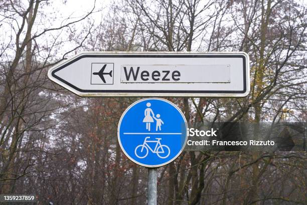Street Sign Shows The Way To The Airport In Weeze Germany Bicycle Lane And Sidewalk Sign Hangs Underneath Stock Photo - Download Image Now