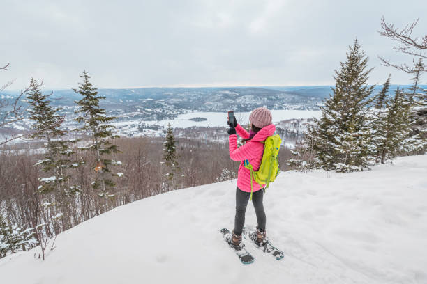 téléphone. randonnerande en raquettes dans la forêt d’hiver à l’aide d’une application téléphonique prenant des photos d’un paysage hivernal idyllique. les gens en randonnée dans la neige vivant un mode de vie actif. mont tremblant, laurenti - snowshoeing snowshoe women shoe photos et images de collection