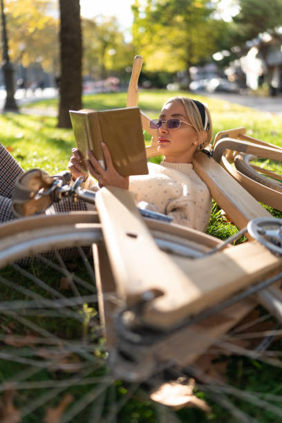 istock Relaxed woman lying on bicycle and reading book 1359242591