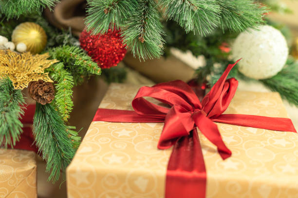 istock Christmas and New Year background. Close-up Xmas tree with decorations and wrapped gift box with red ribbon. Selective focus. Greeting or invitation card. Holiday concept 1359243382