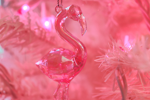 A transparent pink flamingo ornament in a pink Christmas tree.