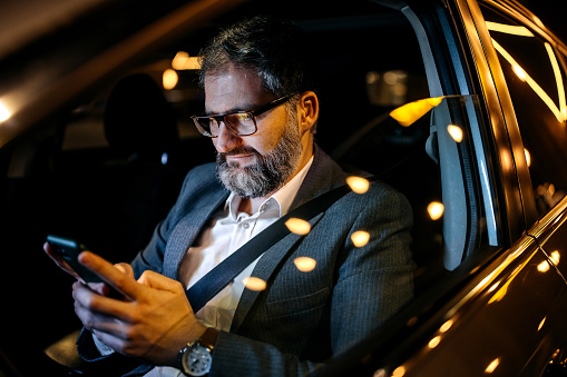 Well dressed businessman texting from his car