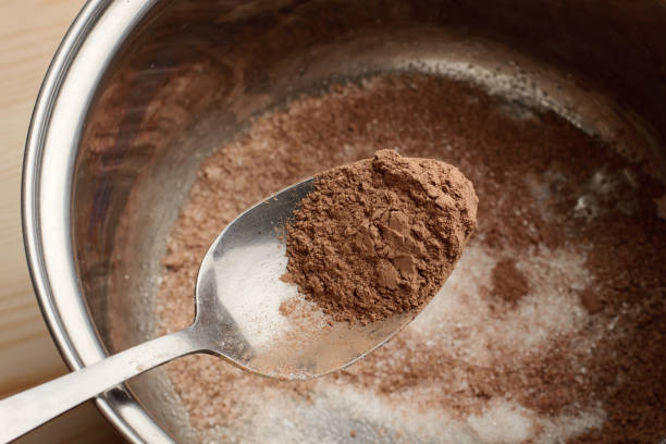 Spoon with cocoa above pot with sugar and cocoa stock photo