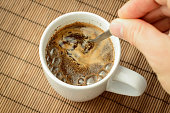 Man`s hand stirs coffee with a spoon
