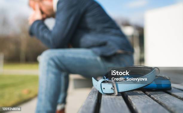 Broken With Grief Man Dog Owner Is Grieving Sitting On A Bench With The Lovely Pet Collar And Deep Weeping About Animal Loss Home Pets Relatives And Love Concept Stock Photo - Download Image Now
