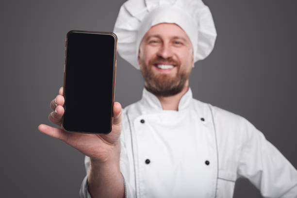 istock Happy chef showing smartphone at camera 1359248134