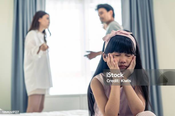 Asian Little Girl Crying While Parents Fighting Or Quarrel Conflict Young Kid Daughter Sit On Bed Feel Heart Broken With Tears And Dont Want To See Violence At Home Family Problemseparation Concept Stock Photo - Download Image Now