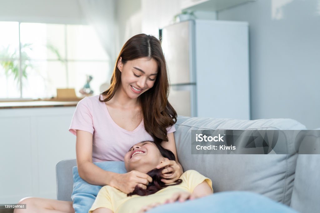 Hermosa pareja de mujeres lesbianas asiáticas acostadas en el regazo de sus novias en casa. Atractivas dos amigas gay se sientan en el sofá de la sala de estar, se sienten felices de pasar tiempo juntas en casa. Concepto homosexual-LGBTQ - Foto de stock de 25-29 años libre de derechos Hermosa pareja de mujeres lesbianas asiáticas acostadas en el regazo de sus novias en casa. Atractivas dos amigas gay se sientan en el sofá de la sala de estar, se sienten felices de pasar tiempo juntas en casa. Concepto homosexual-LGBTQ - Foto de stock de 25-29 años libre de derechos