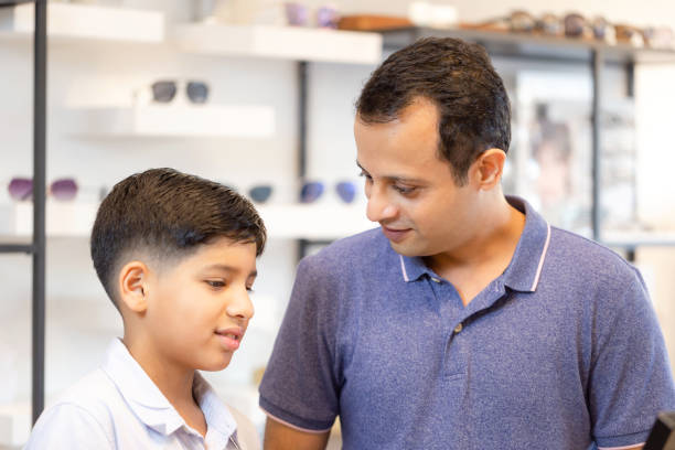 istock Indian boy and father choosing eyeglasses in optics store 1359254366
