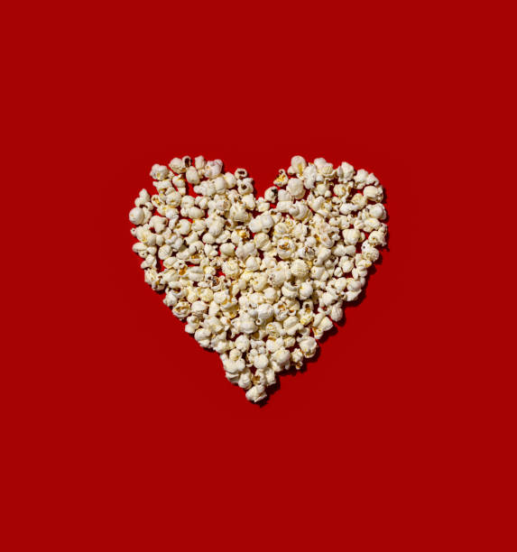 Heart made of popcorn on red color background. Love the cinema, dating, and Valentine's Day concept