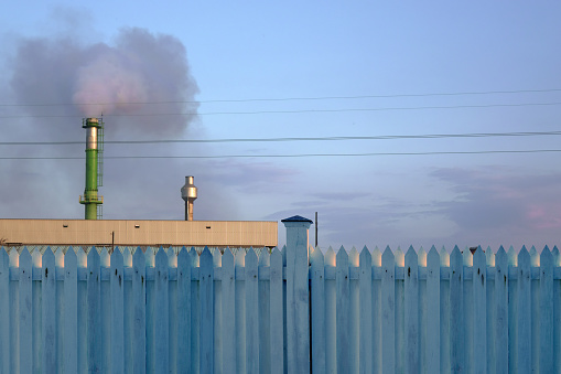 Industrial factory with tall chimney and smoke covered sky