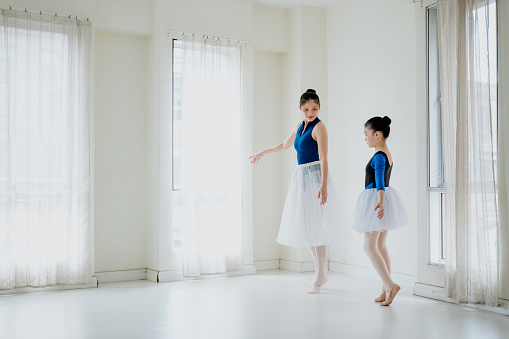 Image of an Asian Chinese woman teaching her daughter ballet dance in studio