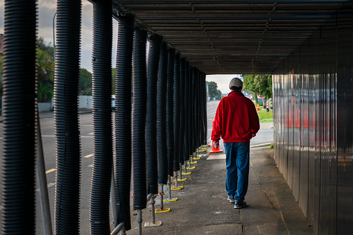 Man walking in the pedestrian walkway tunnel at a construction site.