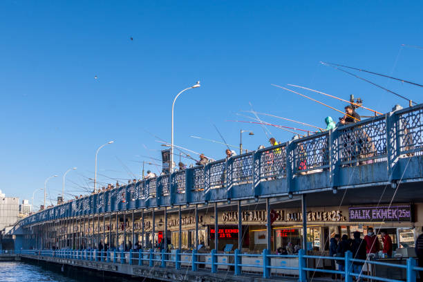 Istanbul, Turkey - December 02, 2021: Eminonu district with many facilities to eat such as floating restaurants and carts with fresh bakery, hot corn or roasted chestnuts in Istanbul, Turkey. People are fishing on Galata Bridge.