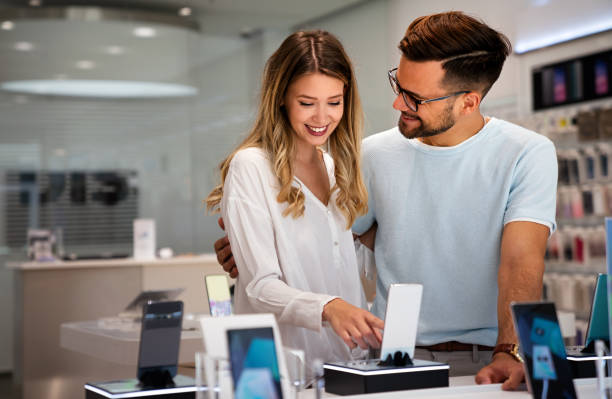 concepto de gadget de dispositivo de compra tecnológica. jóvenes felices comprando un nuevo teléfono inteligente en la tienda móvil. - tienda de electrónica fotografías e imágenes de stock