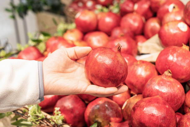 istock A man holding a pomegranate fruit in a supermarket close-up. 1359290414