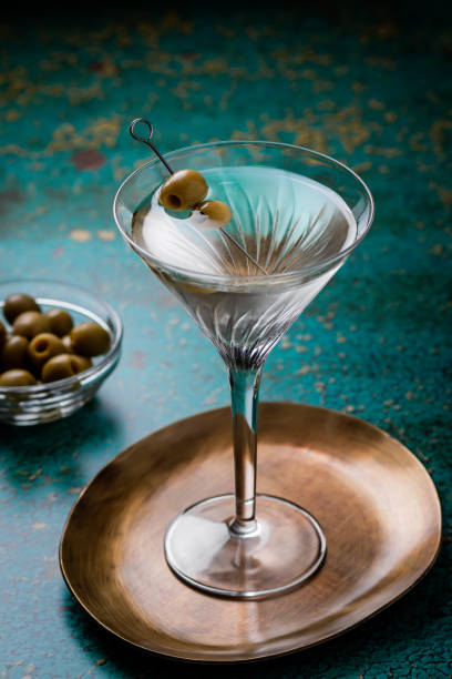 brudny koktajl martini w kieliszku martini z oliwkami na zielonym stole - martini glass martini dirty martini cocktail zdjęcia i obrazy z banku zdjęć