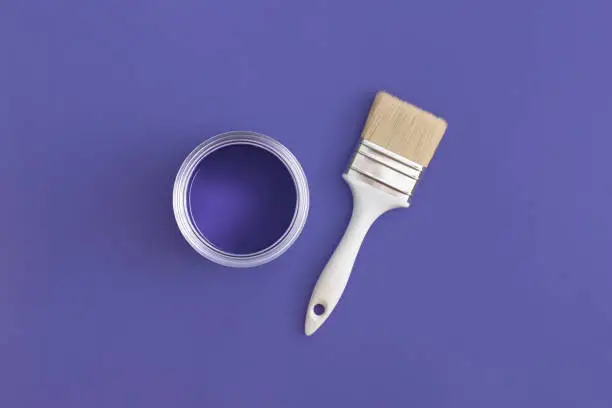 Photo of Paint brush with an open can of paint on trendy Very Peri background. Color of the year 2022. Top view, flat lay.