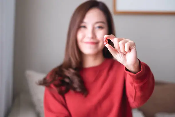 Closeup image of a young woman holding and looking at a red jelly gummy bears