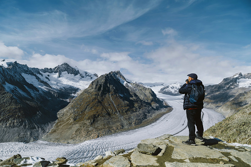 Young Caucasian man taking pictures and walking in nature, aletsch glacier in the background
alpine hiking