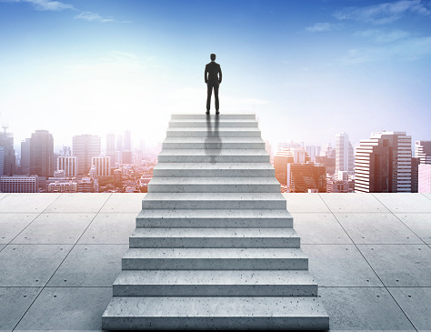 Vision concept. Successful businessman standing on staircase and looking over city