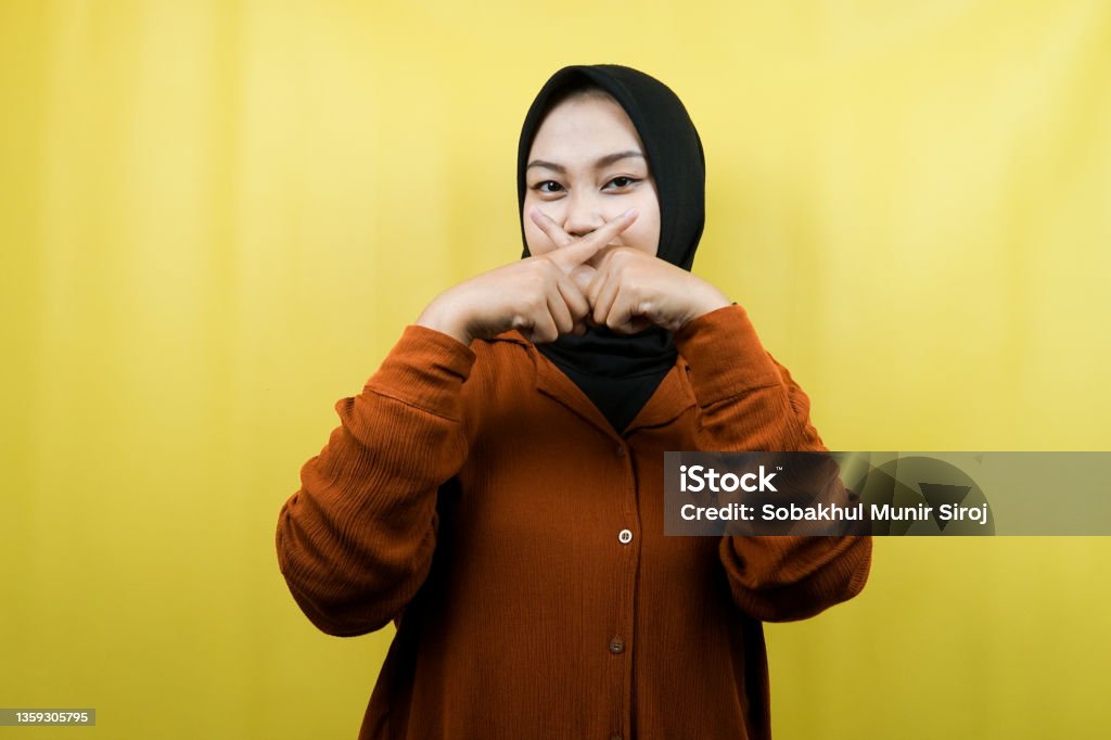Beautiful asian young muslim woman with finger on mouth, telling to be quiet, don't make noise, lower your voice, don't talk, isolated Beauty Stock Photo