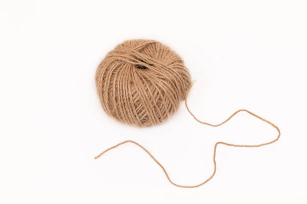 istock photograph of brown threads in a ball on a white background. 1359306784