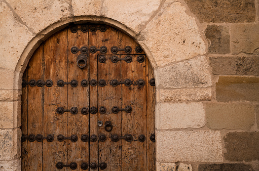 Wooden arched door in stone wall. Shot in Siguenza, Castilla La Mancha, Spain