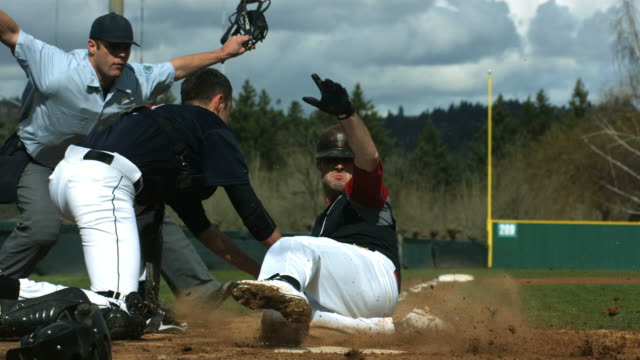 Baseball player slides is safe at home plate, slow motion