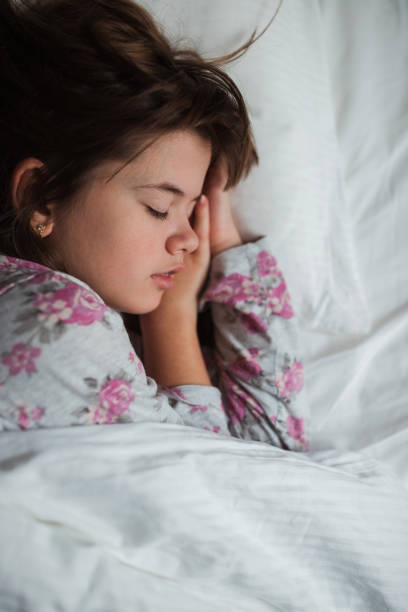 Child holding hands under her head when lying on the side and sleeping peacefully