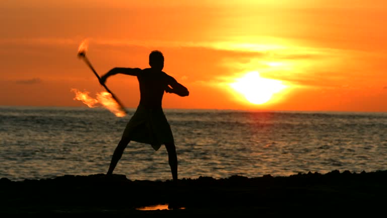 Fire knife dancer performs at sunset