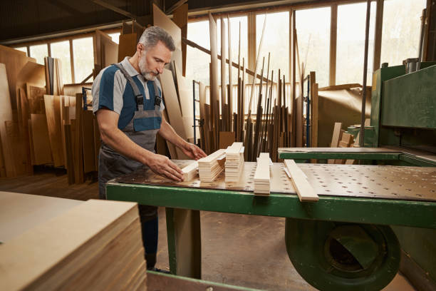 istock Serious mature carpenter collecting wooden bars on table 1359312421
