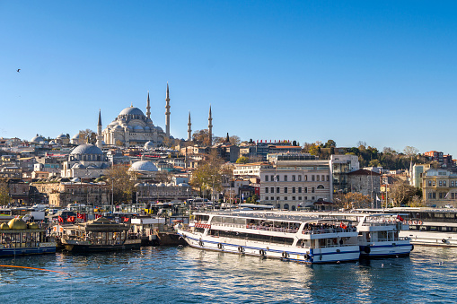 Istanbul, Turkey - December 02, 2021: Eminonu district with many facilities to eat such as floating restaurants and carts with fresh bakery, hot corn or roasted chestnuts in Istanbul, Turkey. Suleymaniye Mosque to hill.