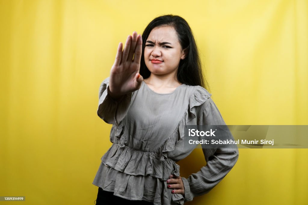 Beautiful young woman with serious expression, refusing something, looking at camera isolated Garbage Stock Photo