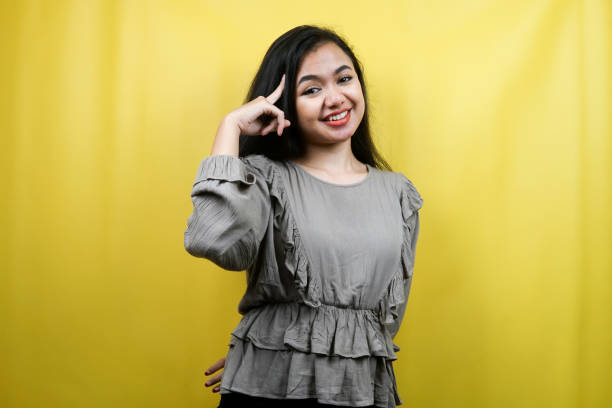 istock Beautiful young woman with finger pointing at head, thinking smart, isolated 1359314953