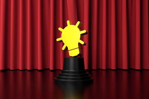 The Light Bulb shaped trophy is on stage in front of the red curtain. Award concept.