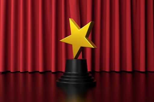 The star shaped trophy is on stage in front of the red curtain. Award concept.