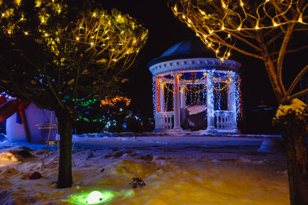 luces iluminadas de la glorieta de invierno nieve nocturna en el suelo. gazebo de vacaciones. luces de navidad afuera en una casa - formal garden front or back yard gazebo night fotografías e imágenes de stock