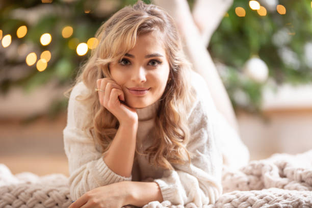 istock Young beautiful smiling blonde lying on a blanket next to a Christmas tree. 1359316425