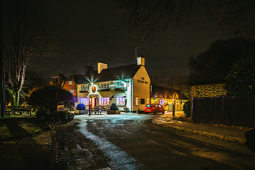 Ifield, UK - 15 December, 2021: color image depicting a quaint, traditional country pub in the old village of Ifield, near Crawley, in the south of England. Night shot with the pub illuminated and decorated with Christmas lights.