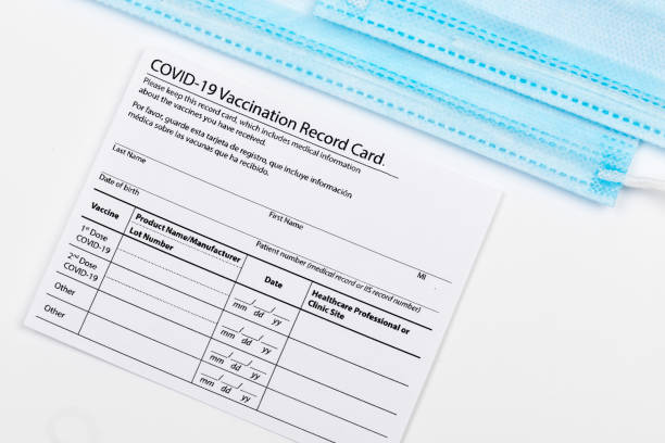 istock Coronavirus vaccination record card. Protective mask divided into two parts. Concept of defeating Covid-19 1359317999