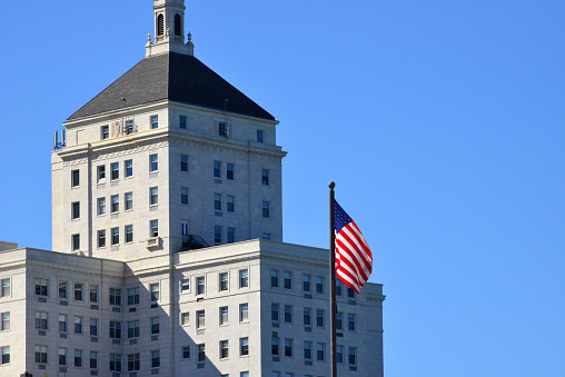 Milwaukee, Wisconsin, USA: the beaux-arts style Cudahy Tower and American Flag, designed by Chicago’s Holabird and Root architect - clad in white glazed brick, with terracotta ornamentation - North Prospect Avenue and East Wells Street, Juneau Town.