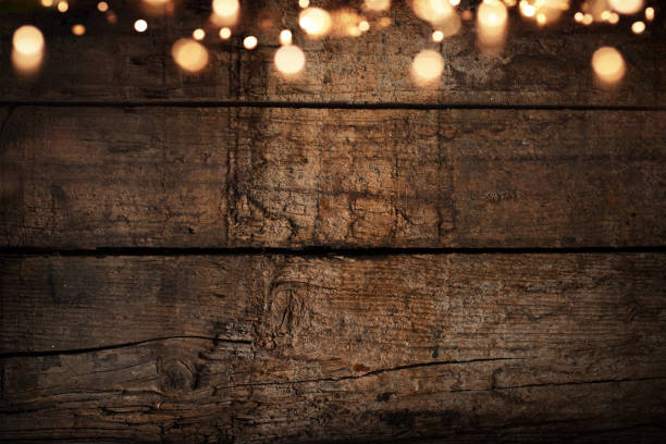 Old rustic wooden wall with fairy light Illuminated old rustic wooden wall with fairy light and golden bokeh lights. Christmas background with space for text. string light stock pictures, royalty-free photos & images