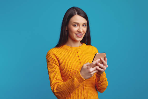 istock Smiling young woman holds modern cellular, sends message in social networks 1359329650