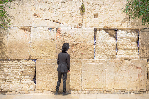The Wailing Wall, Jerusalem, Israel - November 11, 2021: Jewish orthodox believer reading the Torah and praying facing the Western Wall, also known as Wailing Wall in the old city in Jerusalem, Israel.