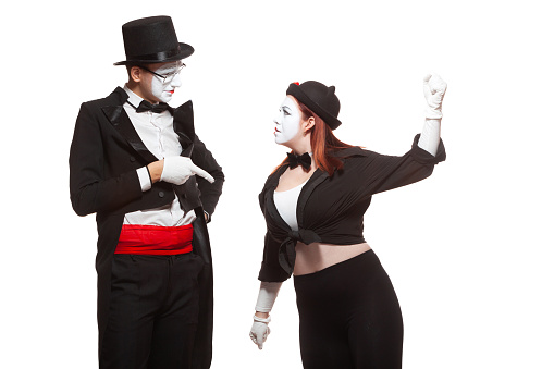 Portrait of two mime artists performing, isolated on white background. Woman raised her fist at the man. Symbol of fight, quarrel, family problems, domestic violence.