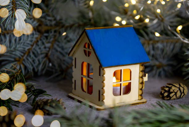 istock selective focus on a small wooden house, a candle will be burning inside, against the background of blurry specks of garlands, the celebration of Christmas and New Year, new dreams and plans 1359331990
