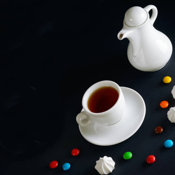 istock Tea cup, teapot and sweets on a black. Free space for text. 1359333414