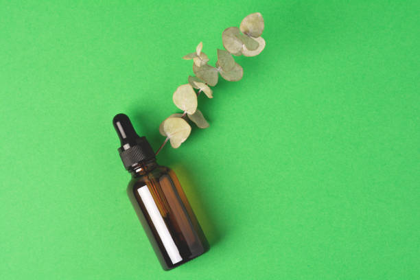 istock Glass bottle with liquid on a green background. 1359335366